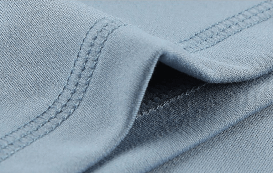 Close-up of blue sporty elastic fabric with stitching details, showing high-quality material of women's training shorts, blend of polyester and spandex.